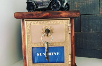 Coin bank made from wood and an old post office box with key in the lock; a metal model mail truck sits on top