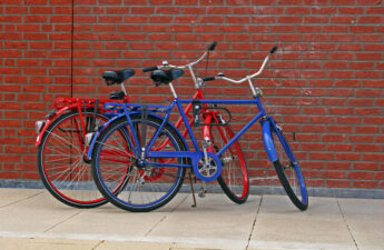 Red and blue bikes in front of a wall of bricks.